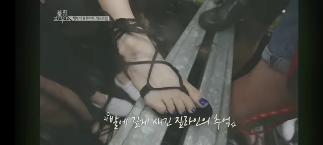 Rosé wearing a delicate strappy sandal in a close-up of her foot and ankle.