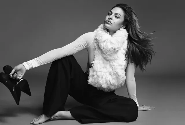 Eva Mendes sitting in a monochrome fashion portrait holding shoes.
