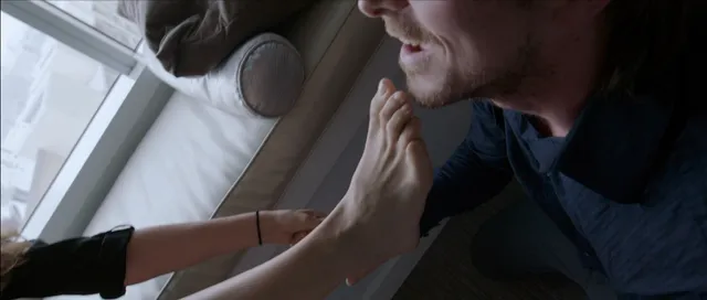 Natalie Portman resting a bare foot beside another person in a film scene.
