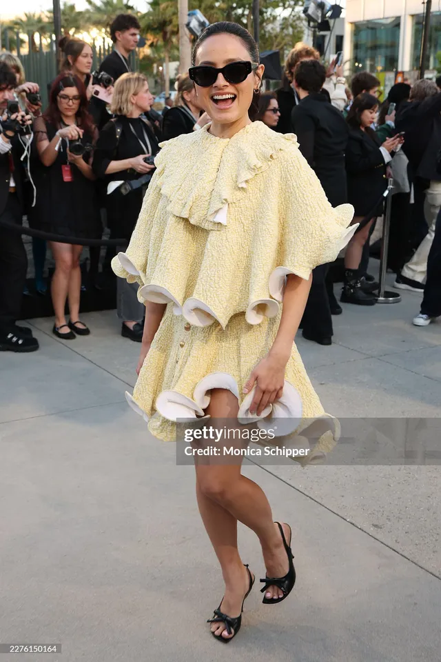 Chase Sui Wonders posing outdoors in a pale cape dress and black heels.