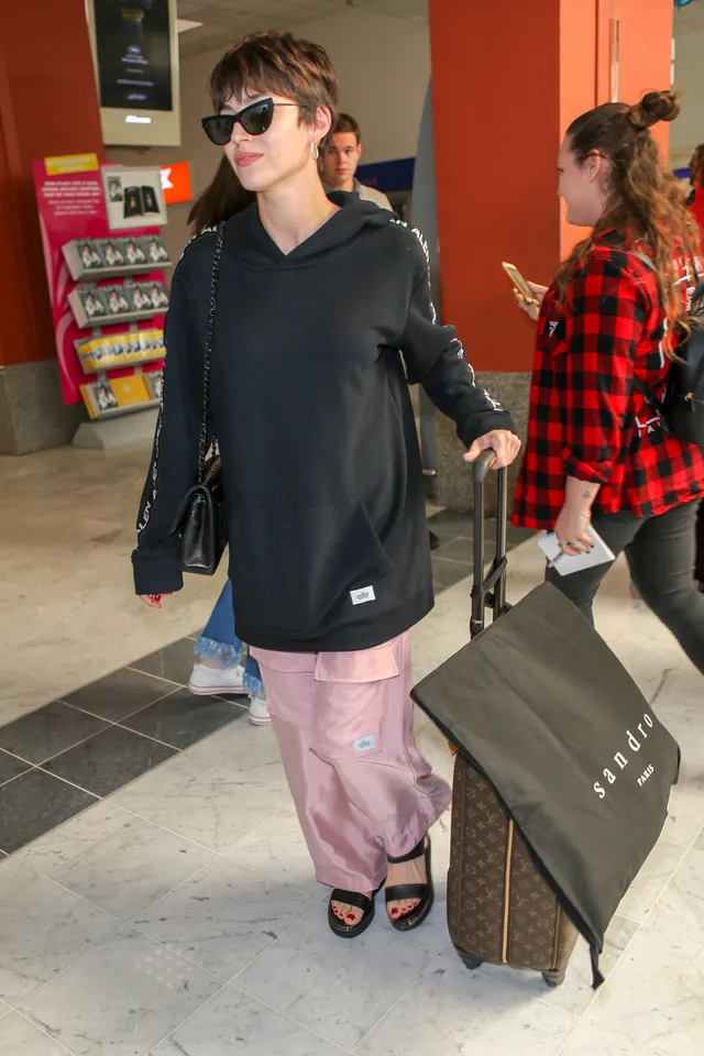 Úrsula Corberó posing indoors in pink trousers, a dark jacket and black heels.