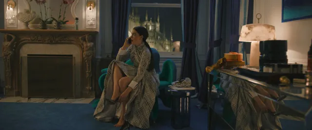 Anne Hathaway sitting with a companion in an indoor screen scene.