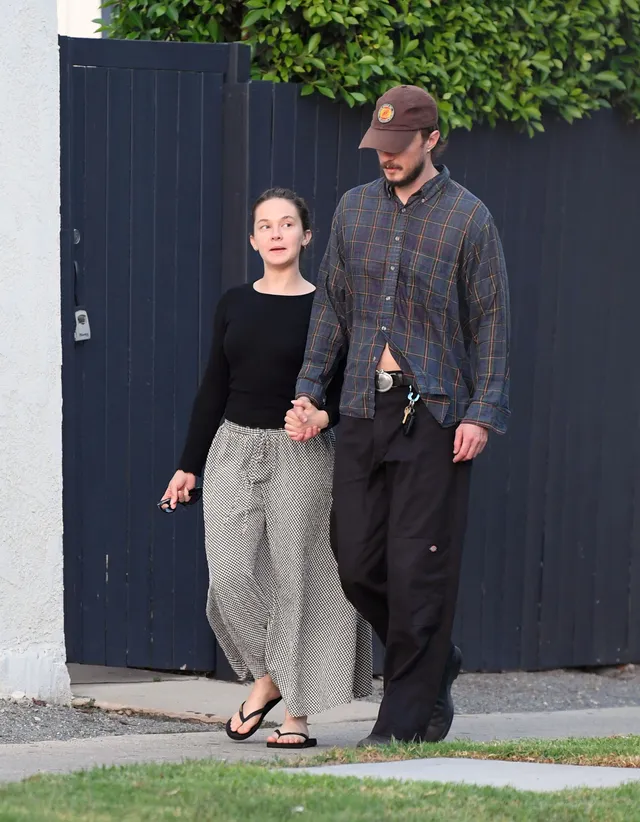 Cailee Spaeny walking outside beside a man in trousers and flip-flops.