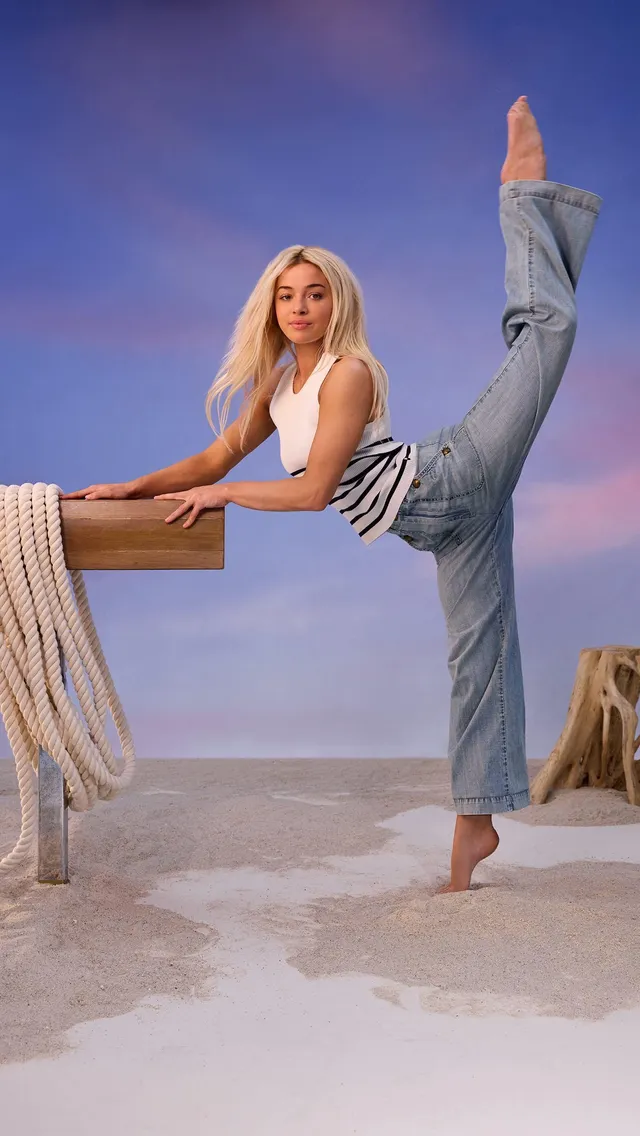 Olivia Dunne: balancing barefoot beside a chair with one leg raised.