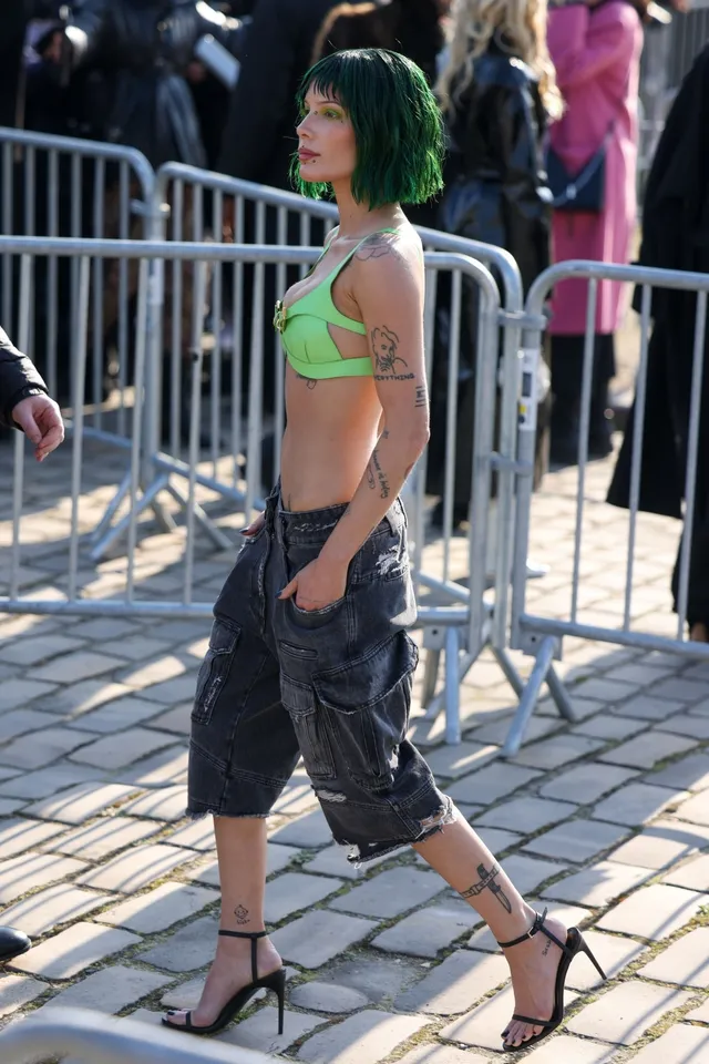 Halsey a green top and black ankle-strap heels outdoors.