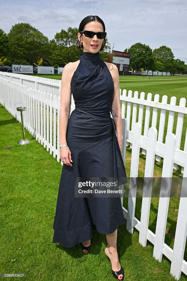 Hayley Atwell posing beside a fence in black sandals.