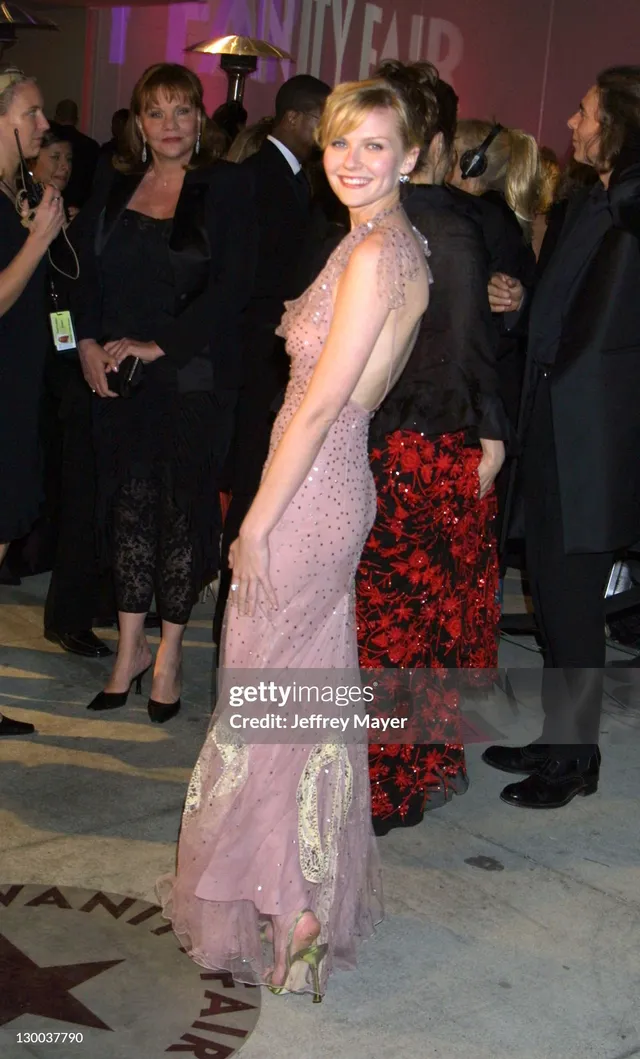 Kirsten Dunst posing in a pink gown at an event.