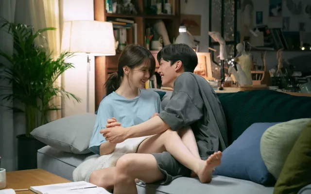 Han So-hee sitting barefoot on a sofa in a scene.