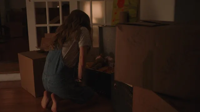 Amanda Seyfried kneeling barefoot beside a bed in a dimly lit screen scene.