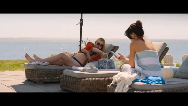 Dakota Fanning reclining barefoot by the water beside another woman.