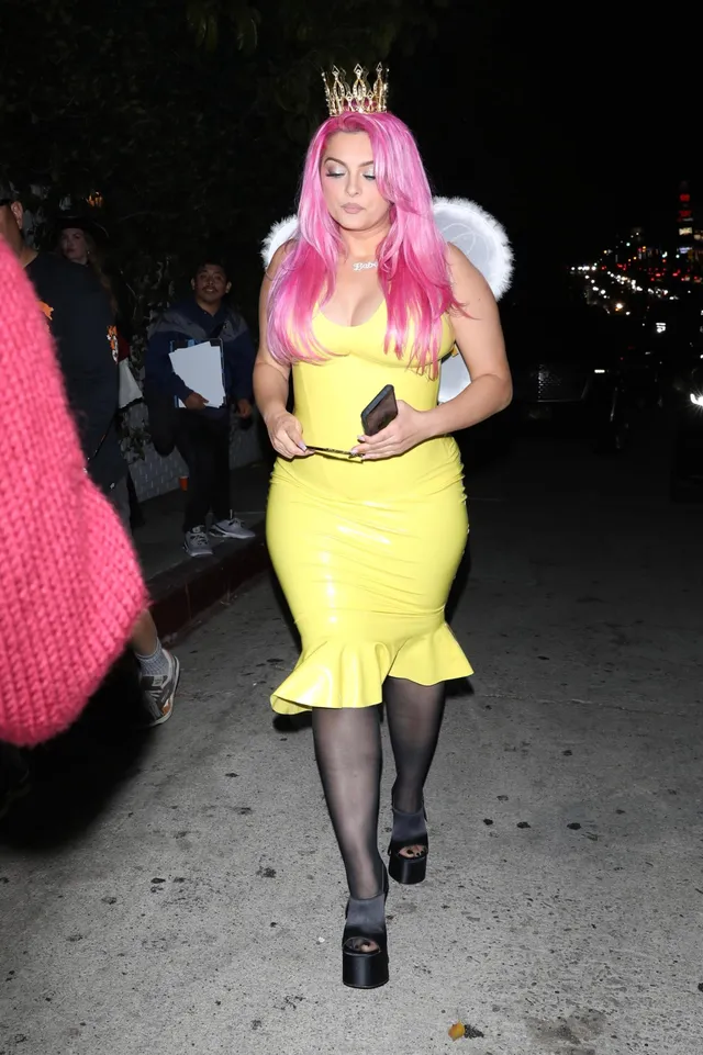 Bebe Rexha walking in a yellow dress and black platform heels.