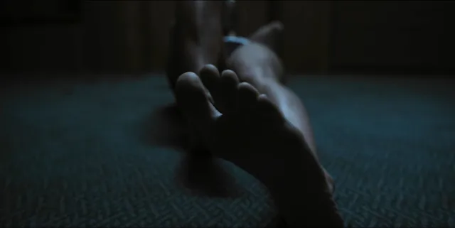 Alice Eve resting her feet on a carpet in a screen scene.