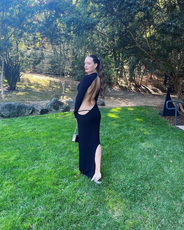 Tove Lo standing barefoot on grass in a black dress.