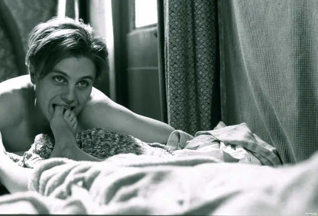 Eva Green lying on a bed in a black and white film scene.