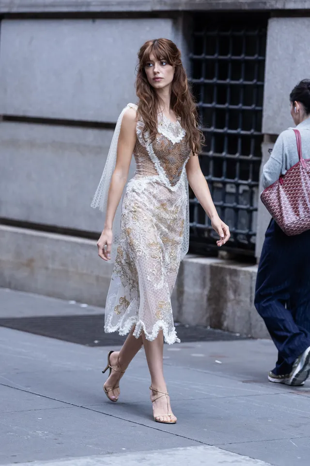 Daisy Edgar-Jones wearing heeled sandals with a pale lace dress outside.