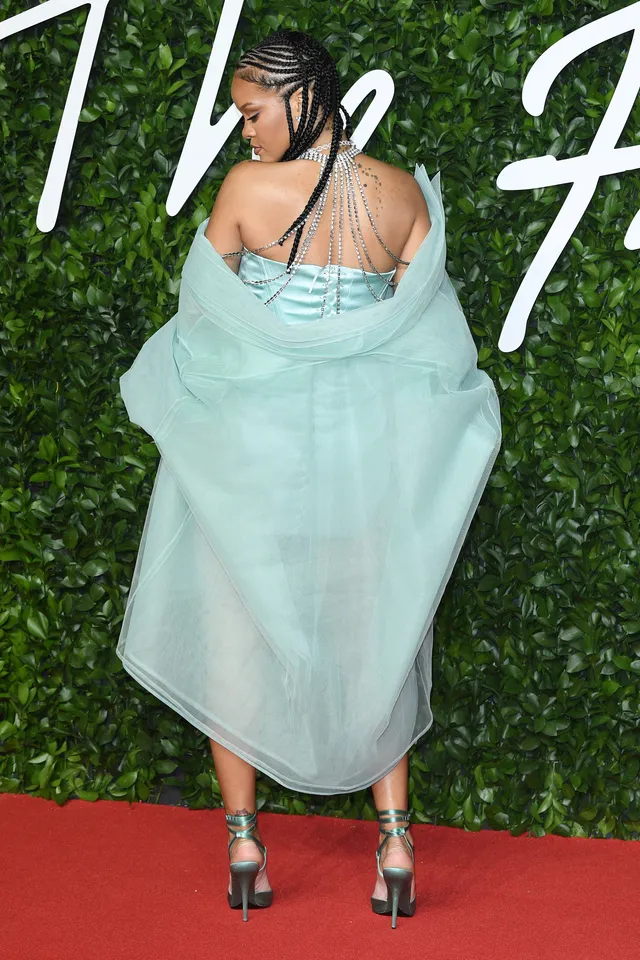 Rihanna wearing a pale green outfit and metallic heels on a red carpet.