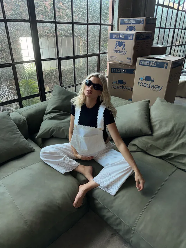 Elsa Hosk sitting cross-legged and barefoot on a green sofa.