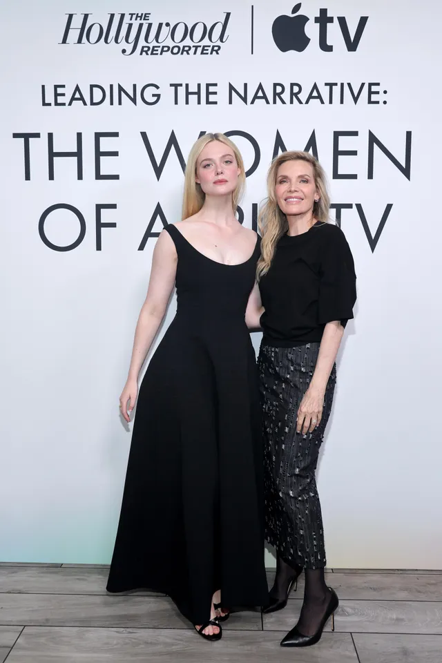 Elle Fanning posing in a black dress beside another woman at an event.