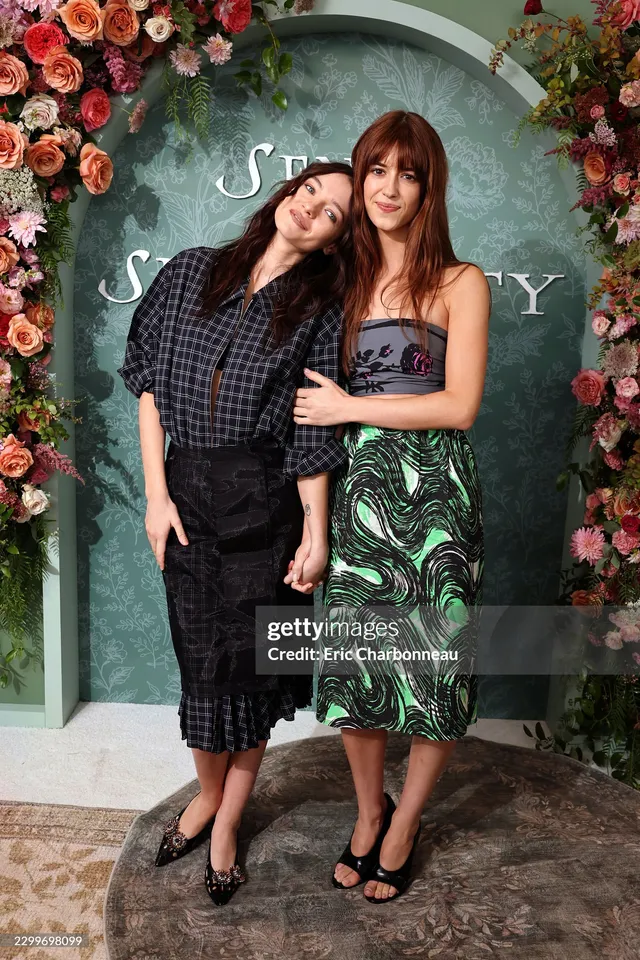 Daisy Edgar-Jones posing with another woman at an event in a patterned dress.