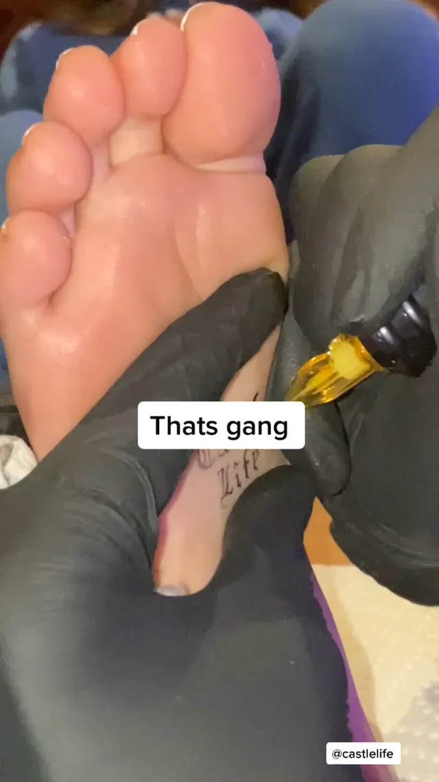 Madison Beer: close view of bare soles held during a tattoo session.