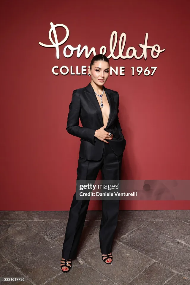 Hande Erçel posing in a black suit at an event.