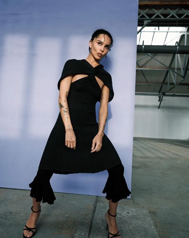 Zoë Kravitz posing in a black dress beside a purple studio backdrop.