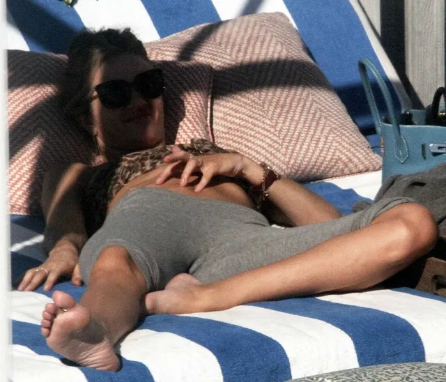 Rosie Huntington-Whiteley a reclining portrait on a striped sunbed.