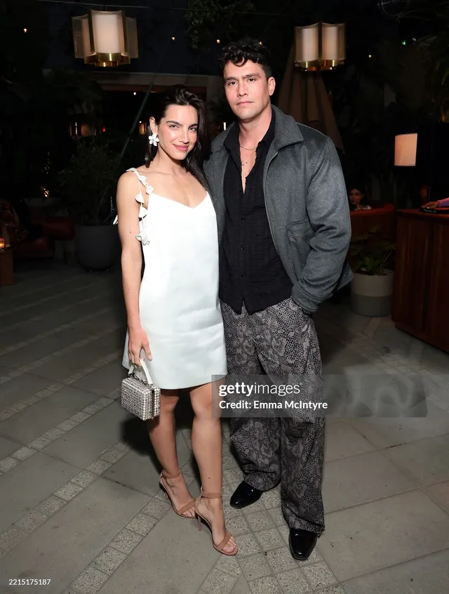 María Gabriela de Faría wearing a white dress and pale heels with a guest.