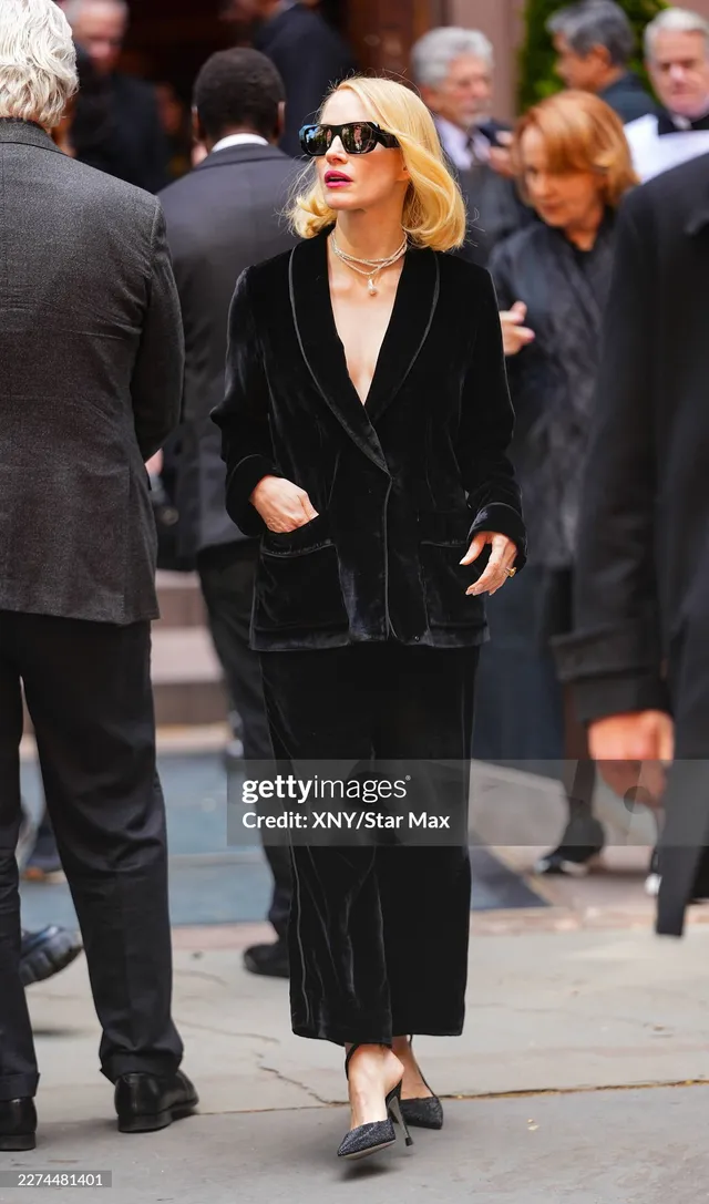 Jessica Chastain standing among guests in black pumps.