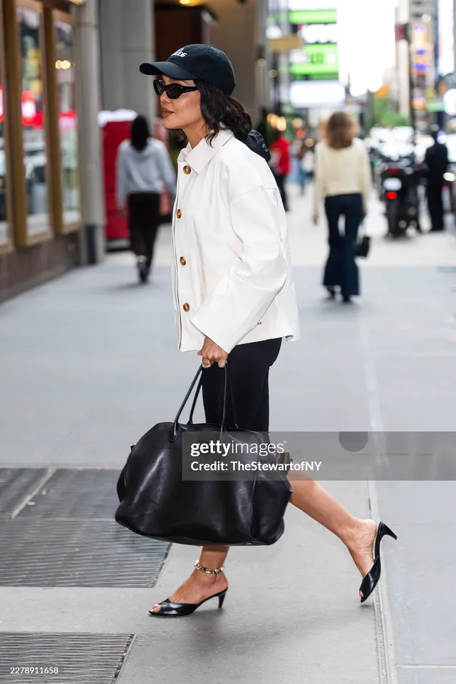 Tessa Thompson walking outside in a white jacket and dark skirt.