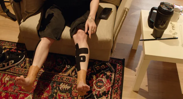 Billie Eilish a seated detail of taped ankles and bare feet.