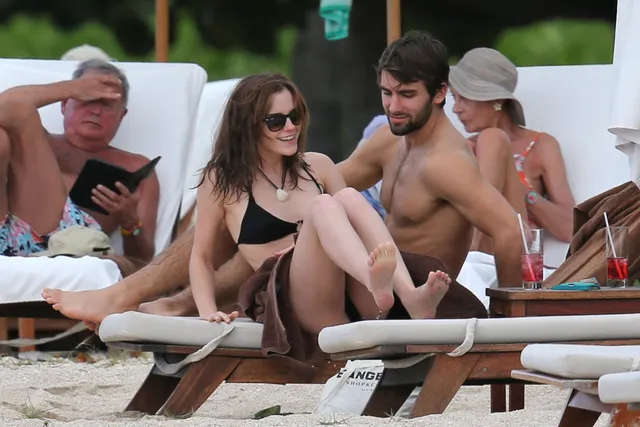 Emma Watson: seated barefoot on an outdoor lounger with friends.