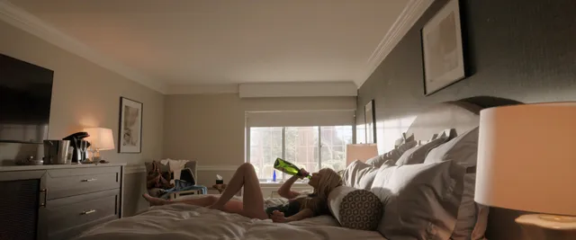 Amanda Seyfried reclining barefoot on a bed in a screen scene.
