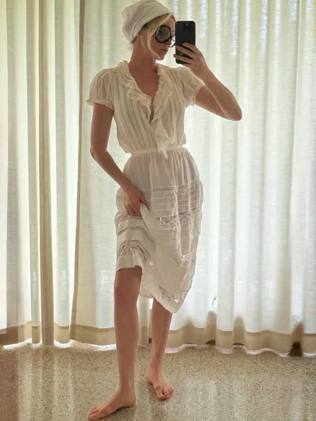 Elsa Hosk taking a barefoot mirror photograph in a pale dress.