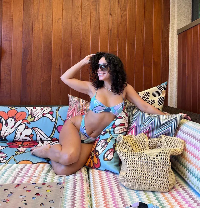 Vanessa Hudgens sitting barefoot on a colorful outdoor sofa.