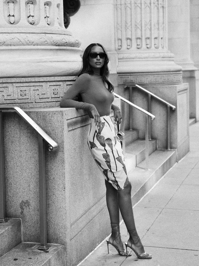 Jasmine Tookes wearing heels with a patterned skirt in a monochrome outdoor portrait.