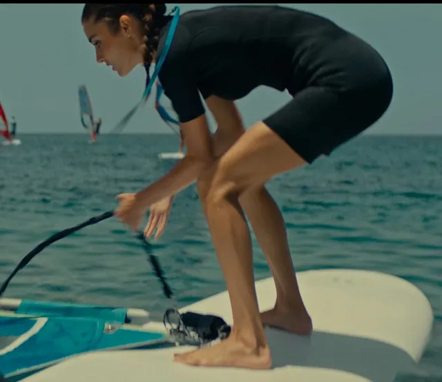 Hande Erçel crouching barefoot on a boat.