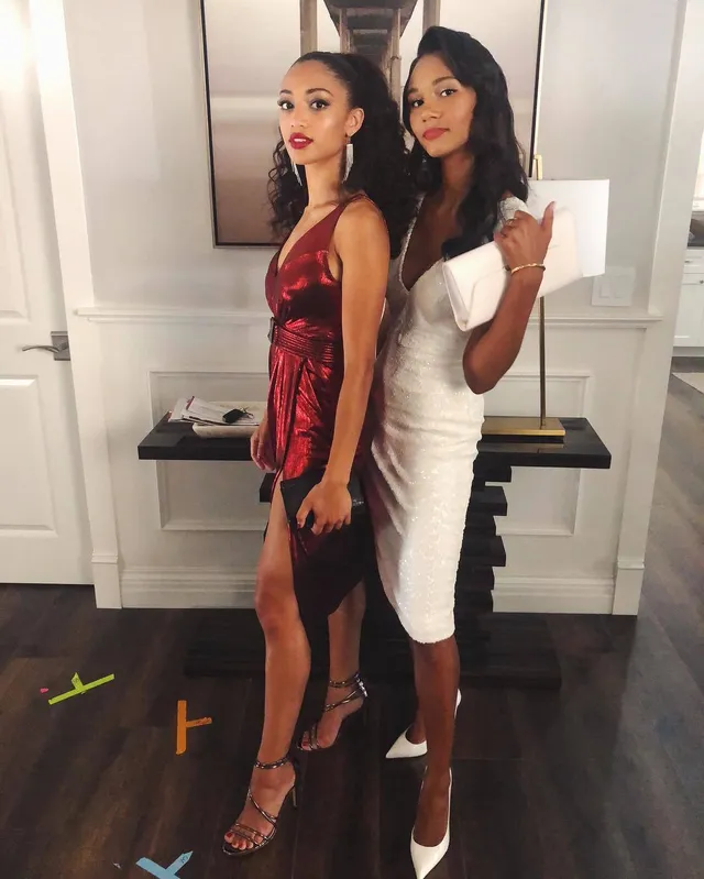 Samantha Logan posing beside a friend in a white dress and pointed heels.
