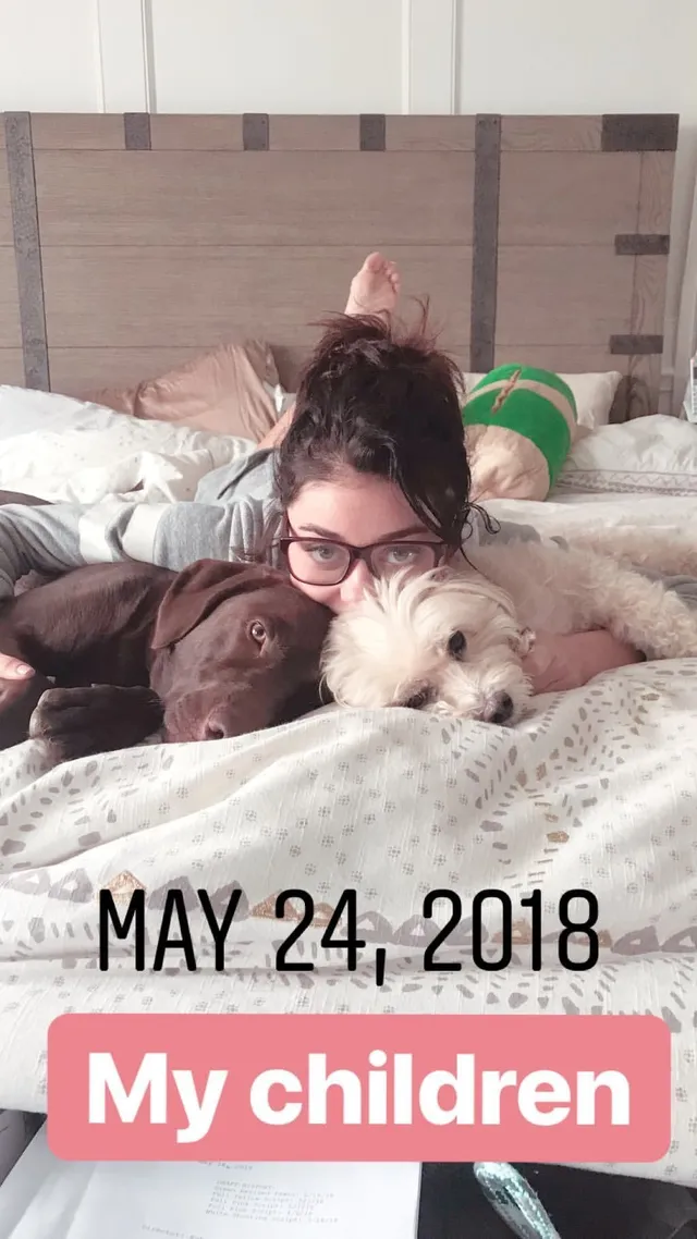 Sarah Hyland lying on a bed beside dogs.