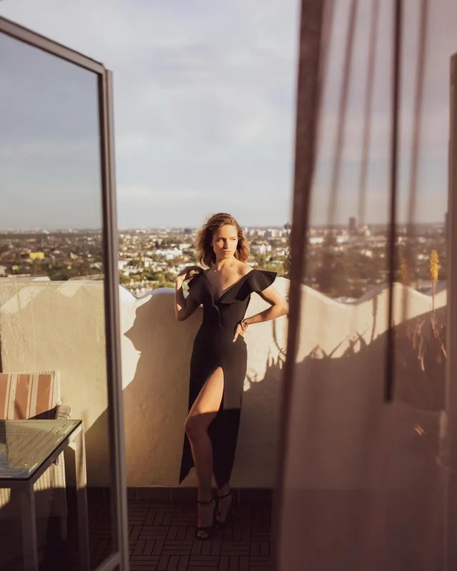 Dianna Agron posing on a balcony in a dark dress.