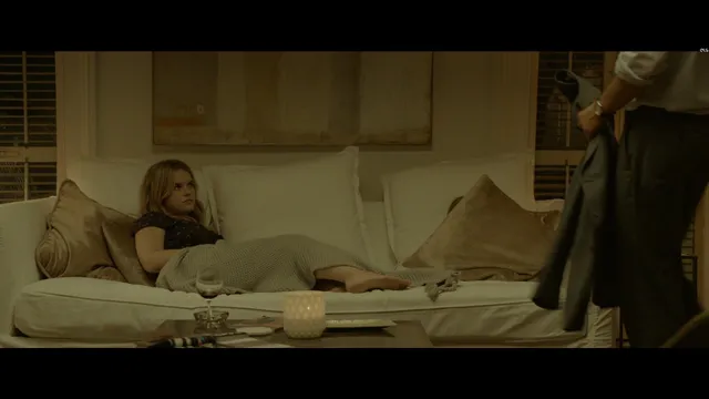Alice Eve reclining on a sofa in a screen scene.