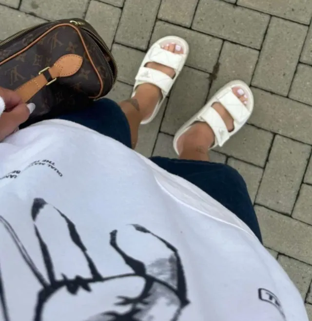 Alisha Lehmann wearing white flat sandals in an overhead outdoor photograph.