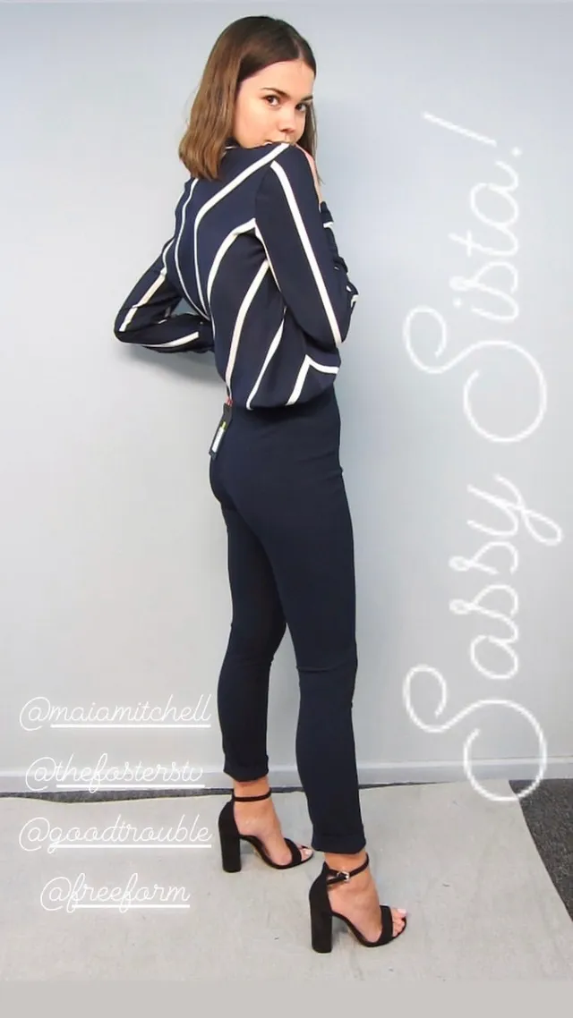 Maia Mitchell posing in a striped top and black heels.