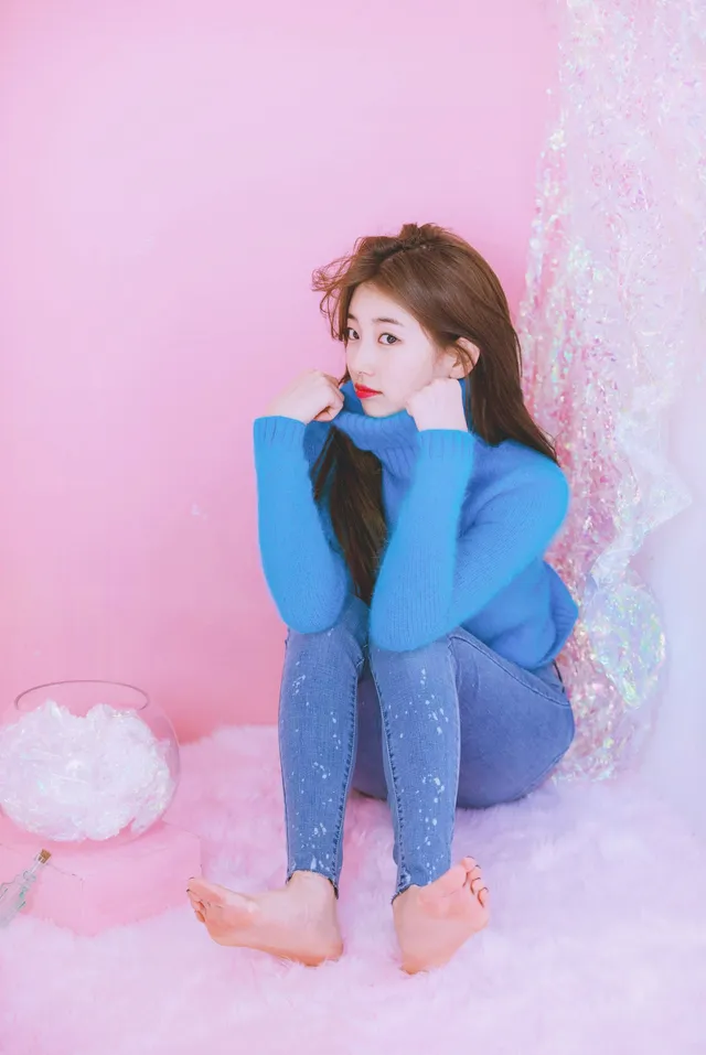 Bae Suzy sitting barefoot against a pink backdrop.
