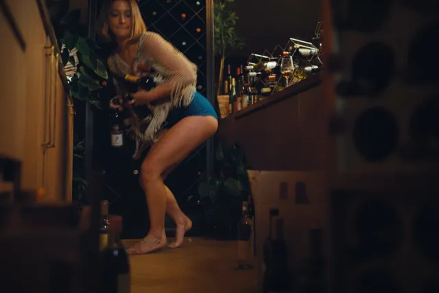 Madelyn Cline bending down barefoot in a bar scene.