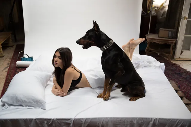 Madison Beer: reclining barefoot on a white bed beside a dog.