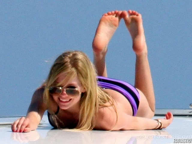Avril Lavigne lying on a boat with her bare soles raised.