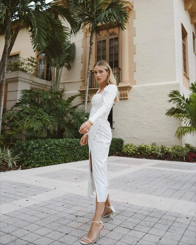 Claire Holt standing outdoors in a pale outfit and sandals.