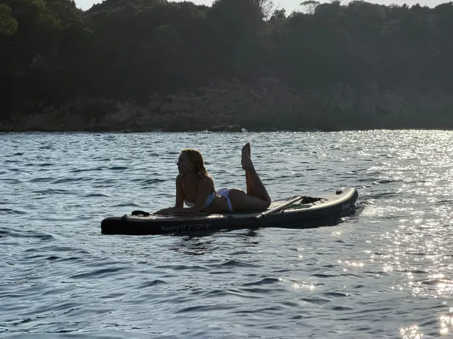 Ester Expósito lying barefoot on a paddleboard on a lake.