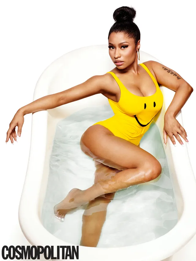 Nicki Minaj sitting barefoot in a bathtub in a magazine photograph.